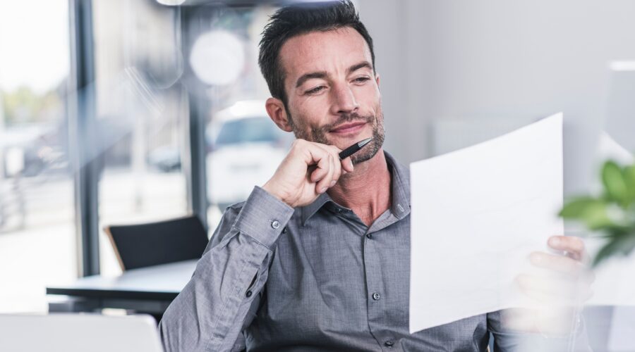 Businessman sitting in office, reading a letter