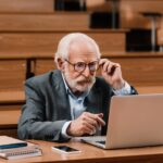 grey hair professor looking at laptop