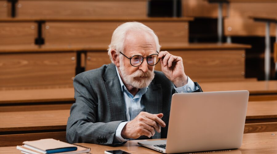 grey hair professor looking at laptop