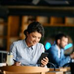 Young businesswoman reading text message on smart phone in a cafe.