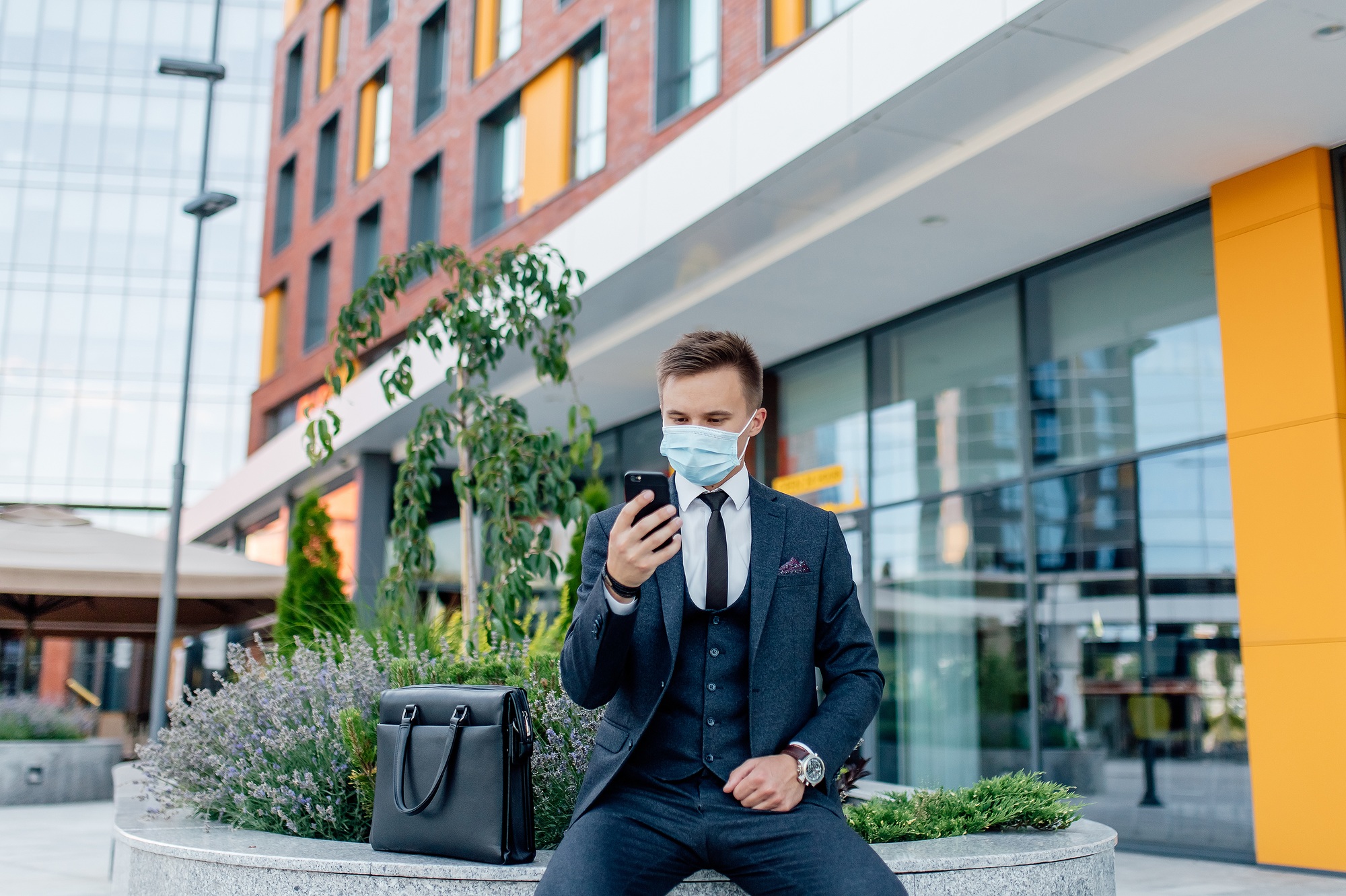 businessman in formal suit and medical mask messaging on smartphone