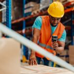 Focused warehouse worker scanning package with barcode scanner