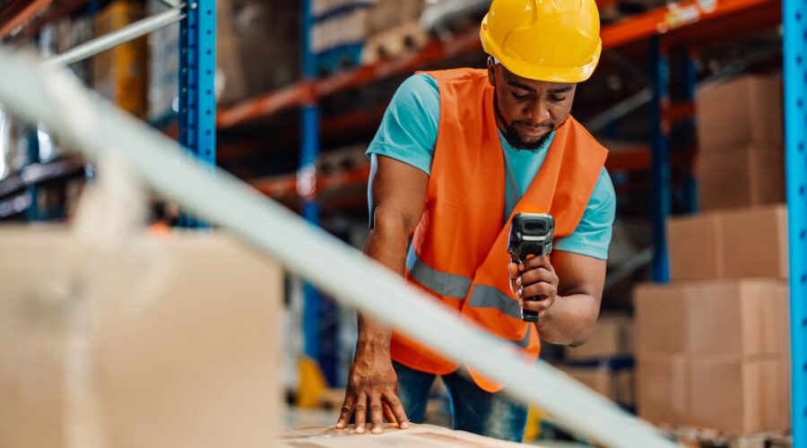 Focused warehouse worker scanning package with barcode scanner