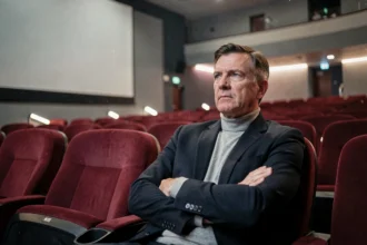 Critique de cinéma pensif assis dans une salle vide après la projection du film Sous écrous en 2026